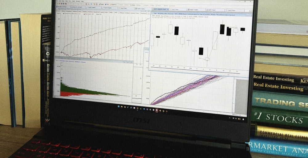 A RealTest backtest open on a laptop next to trading books